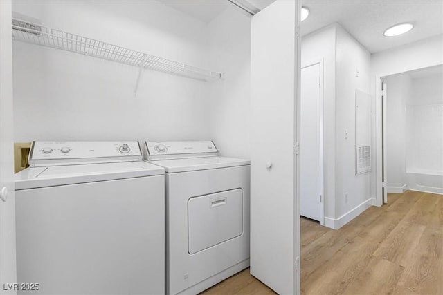 clothes washing area featuring washer and clothes dryer and light wood-type flooring