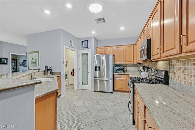 kitchen with sink, backsplash, light tile patterned floors, light stone counters, and stainless steel appliances