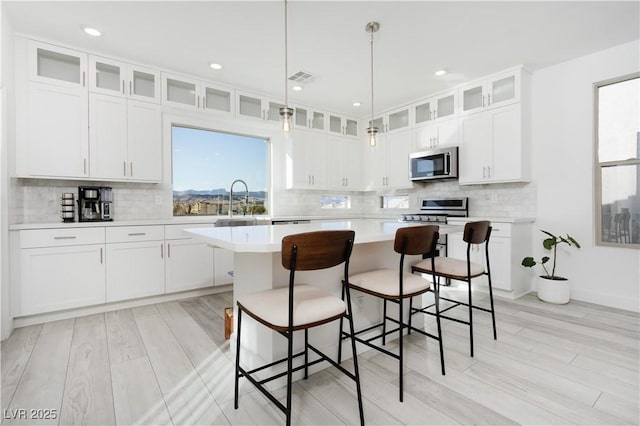 kitchen featuring a kitchen island, a kitchen breakfast bar, white cabinets, and appliances with stainless steel finishes