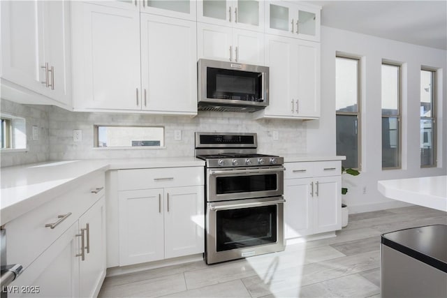 kitchen with appliances with stainless steel finishes, decorative backsplash, and white cabinets