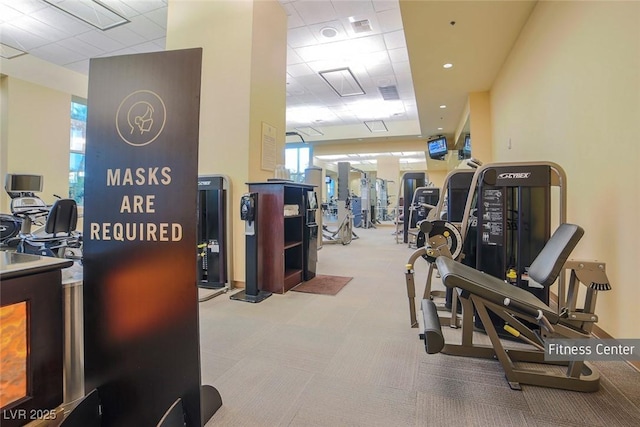 gym with a drop ceiling, visible vents, and light colored carpet