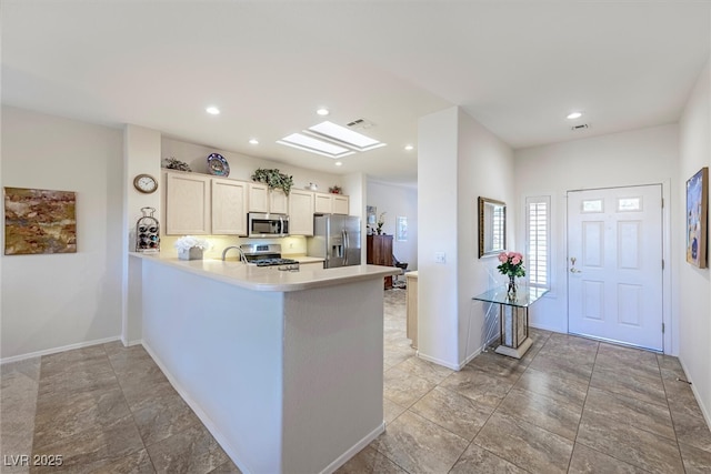 kitchen featuring a skylight, stainless steel appliances, kitchen peninsula, and sink