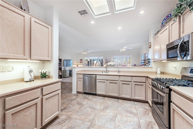 kitchen featuring sink, light brown cabinets, kitchen peninsula, and appliances with stainless steel finishes