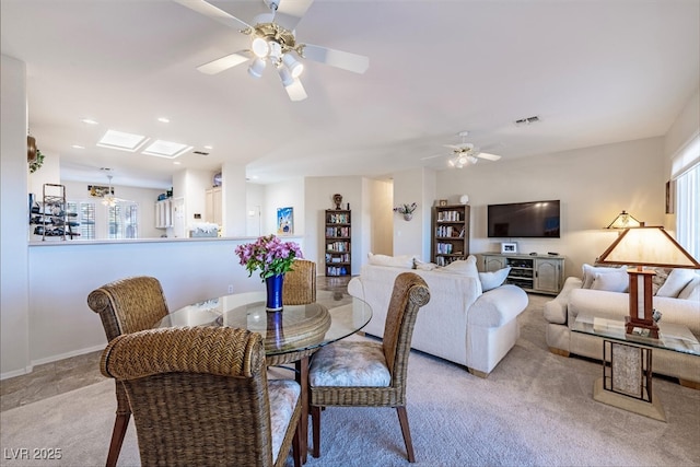 dining room with a skylight, light colored carpet, and ceiling fan