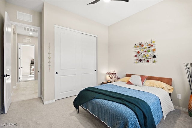 bedroom with light colored carpet, ceiling fan, and a closet