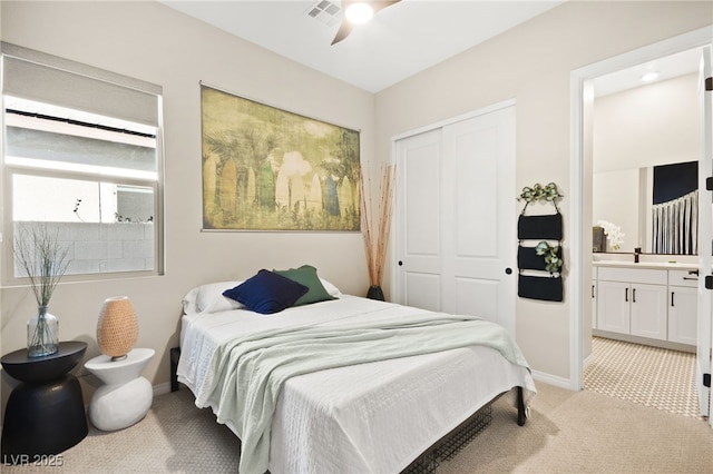 bedroom with connected bathroom, light colored carpet, a closet, and ceiling fan