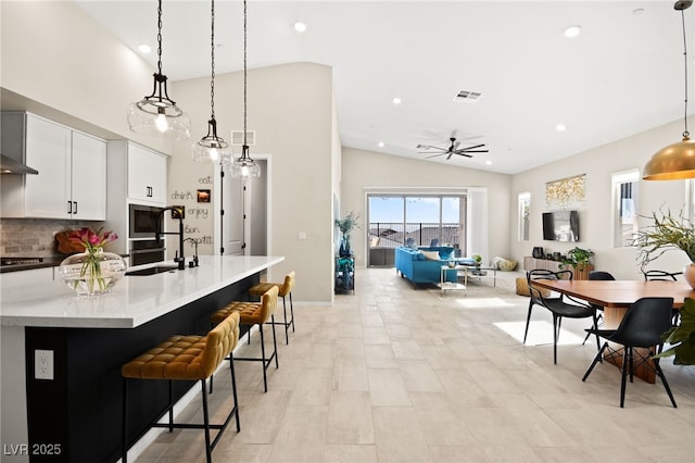 kitchen with stovetop, sink, white cabinetry, a kitchen breakfast bar, and pendant lighting