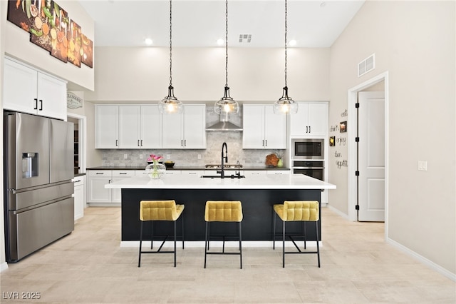 kitchen featuring appliances with stainless steel finishes, a kitchen island with sink, hanging light fixtures, and white cabinets