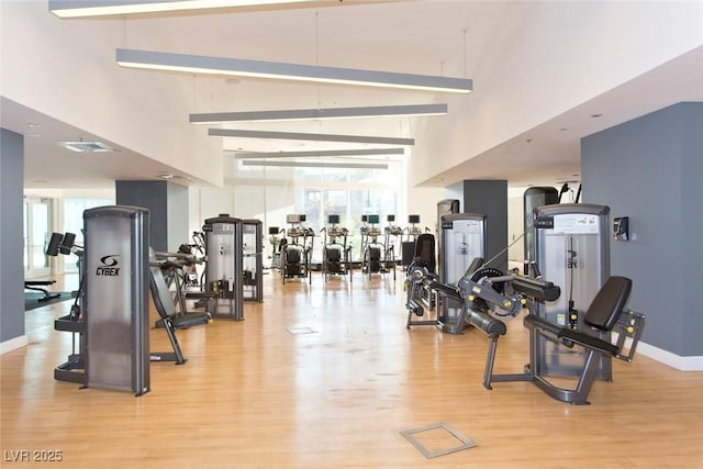 exercise room with a high ceiling and light wood-type flooring