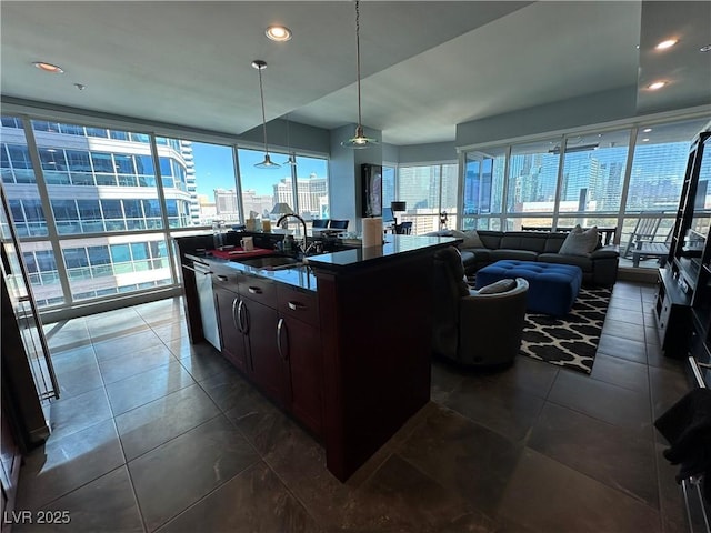 kitchen with pendant lighting, sink, a wealth of natural light, and a center island with sink