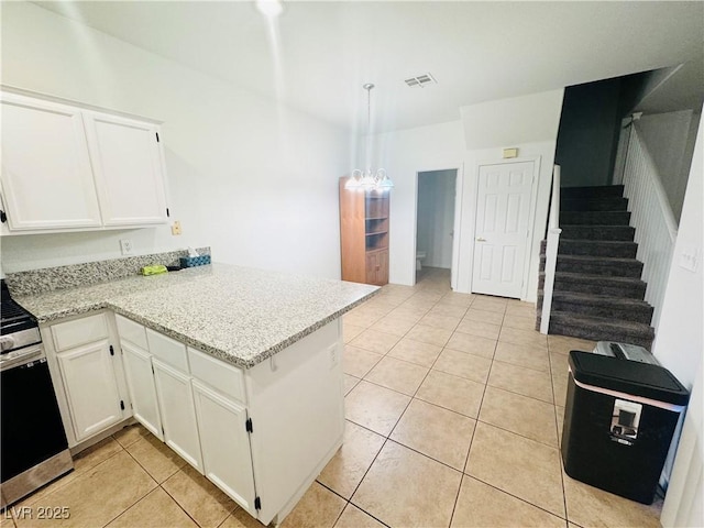 kitchen with light stone counters, light tile patterned floors, kitchen peninsula, and white cabinets