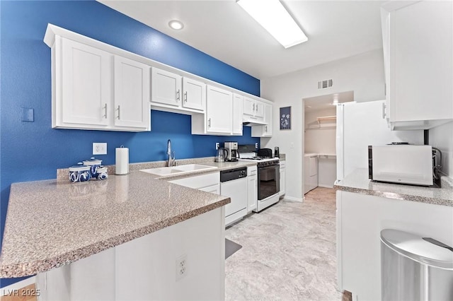 kitchen featuring sink, white appliances, washing machine and clothes dryer, white cabinets, and kitchen peninsula