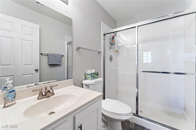 bathroom with vanity, a shower with door, and toilet