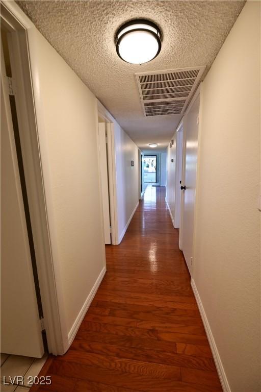 corridor with dark hardwood / wood-style floors and a textured ceiling