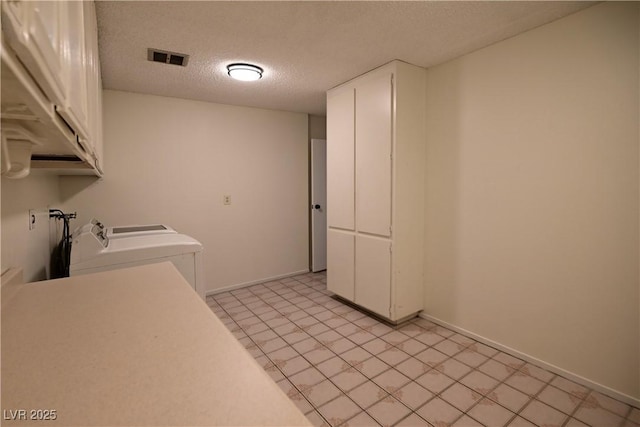 laundry room with cabinets, washer / dryer, and a textured ceiling