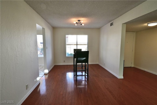 unfurnished dining area with dark hardwood / wood-style floors and a textured ceiling