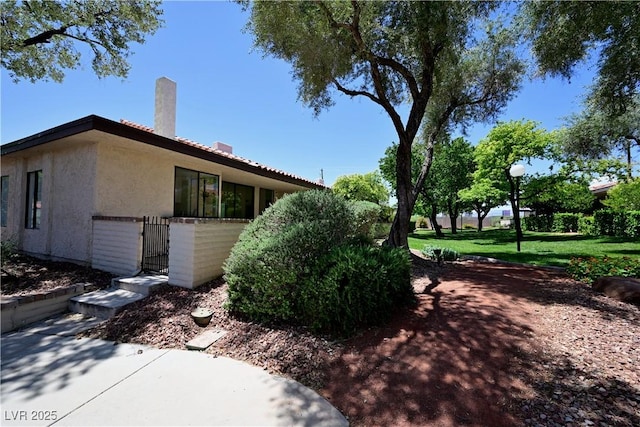 3126 Asoleado Cir, Las Vegas, NV 89121 - view of side of home featuring stucco siding, a gate, and a chimney