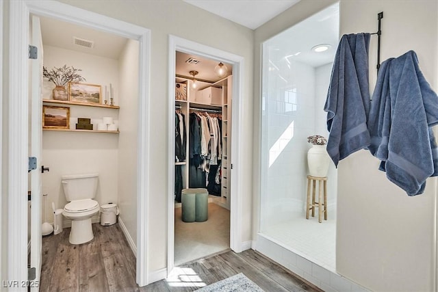 bathroom with hardwood / wood-style floors, toilet, and walk in shower