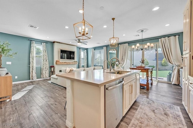 kitchen featuring hanging light fixtures, dishwasher, a kitchen island with sink, and sink