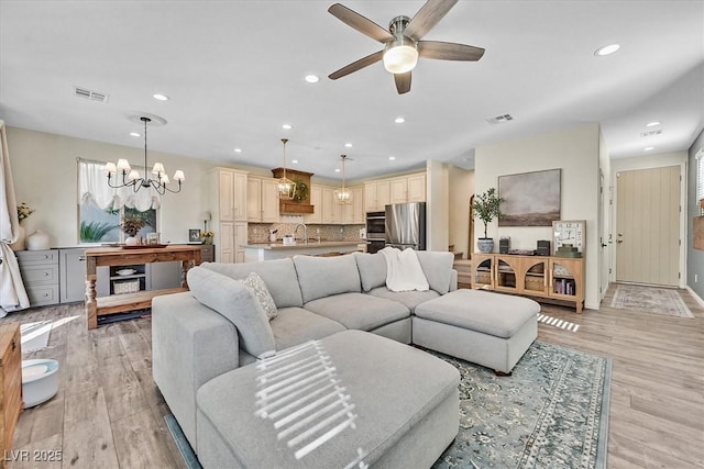 living room featuring sink, ceiling fan with notable chandelier, and light hardwood / wood-style flooring