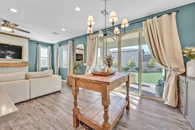 dining area with ceiling fan with notable chandelier and light hardwood / wood-style floors