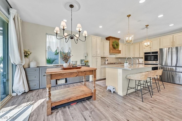 kitchen featuring appliances with stainless steel finishes, decorative light fixtures, backsplash, a chandelier, and a kitchen breakfast bar