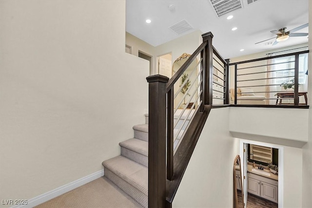 stairway with ceiling fan and carpet