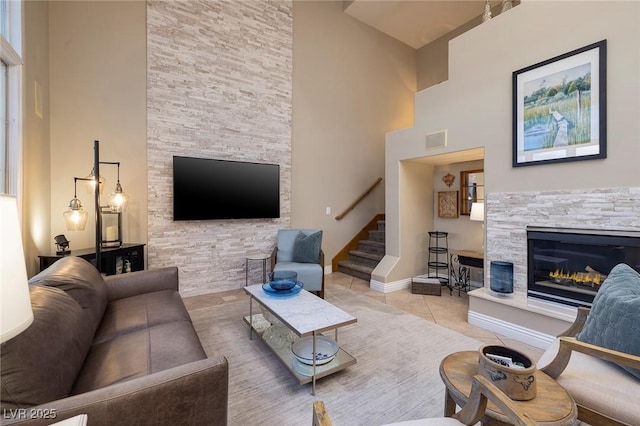 living room featuring a high ceiling, a stone fireplace, and light tile patterned floors