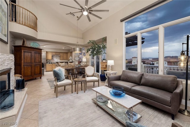 living room with high vaulted ceiling, a stone fireplace, light tile patterned floors, and ceiling fan