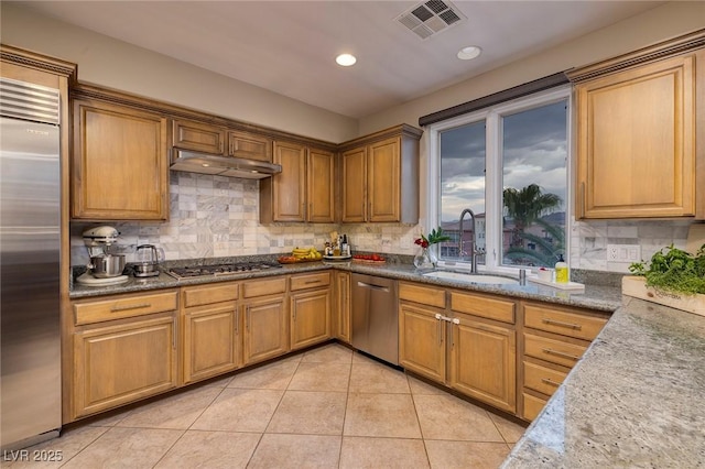 kitchen with appliances with stainless steel finishes, sink, light tile patterned floors, and backsplash