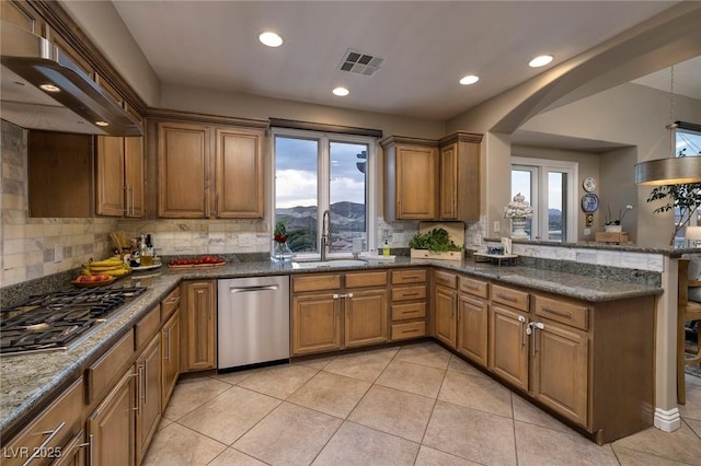 kitchen with sink, extractor fan, appliances with stainless steel finishes, a mountain view, and kitchen peninsula