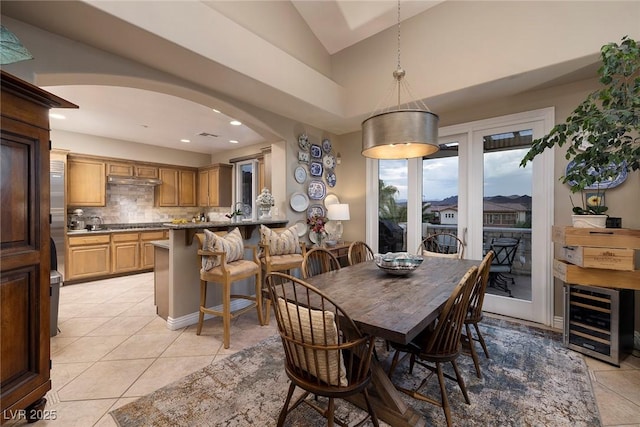 dining area featuring light tile patterned flooring, vaulted ceiling, and beverage cooler