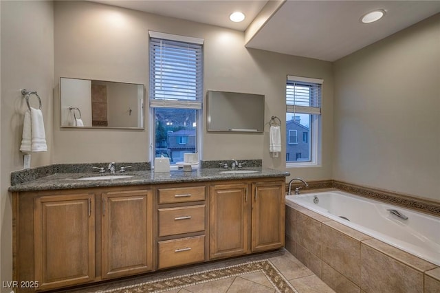 bathroom featuring tiled tub, vanity, and tile patterned floors