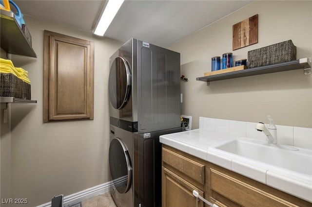 washroom featuring cabinets, sink, and stacked washer and clothes dryer