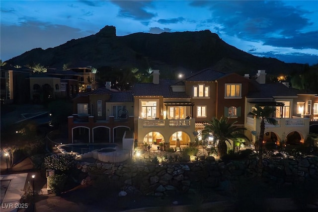 back house at dusk featuring a balcony and a mountain view