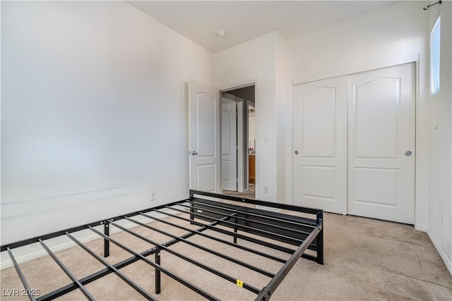 unfurnished bedroom with light colored carpet and a closet