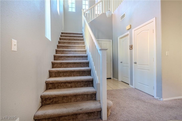 stairs with a high ceiling and carpet flooring