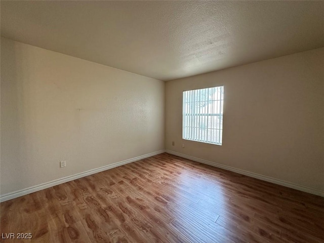 unfurnished room featuring hardwood / wood-style flooring and a textured ceiling