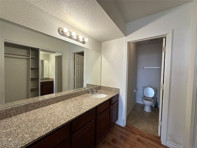 bathroom with vanity, hardwood / wood-style floors, a textured ceiling, and toilet