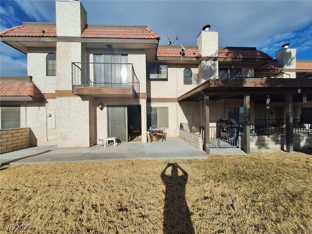 back of property featuring a balcony, a yard, and a patio