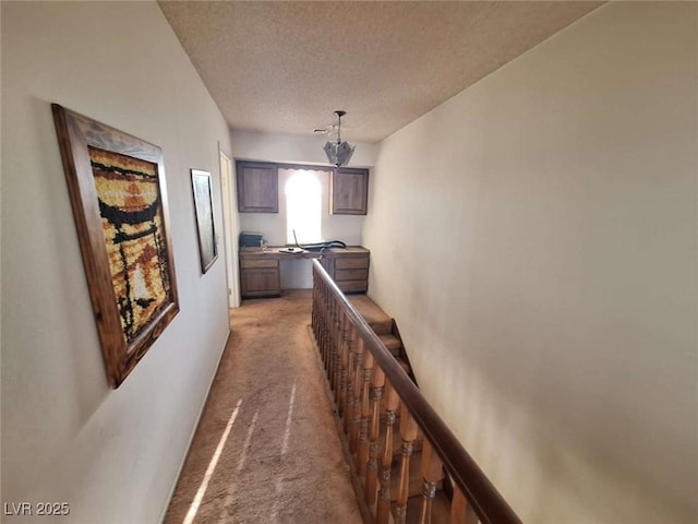 hallway with light carpet and a textured ceiling