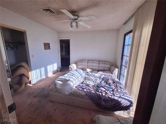 carpeted bedroom with ceiling fan, a closet, and a textured ceiling