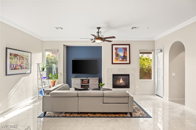 living room featuring ornamental molding, a wealth of natural light, a tile fireplace, and ceiling fan