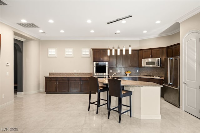 kitchen with an island with sink, a kitchen breakfast bar, light stone counters, stainless steel appliances, and dark brown cabinets