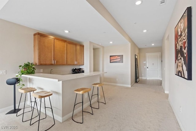 kitchen with a breakfast bar, kitchen peninsula, and light colored carpet