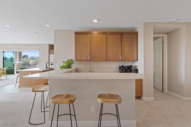 kitchen with sink, light tile patterned floors, kitchen peninsula, and a breakfast bar