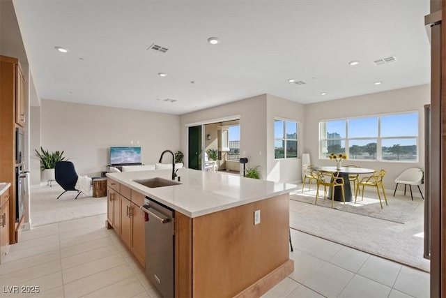 kitchen with light colored carpet, stainless steel dishwasher, sink, and a center island with sink