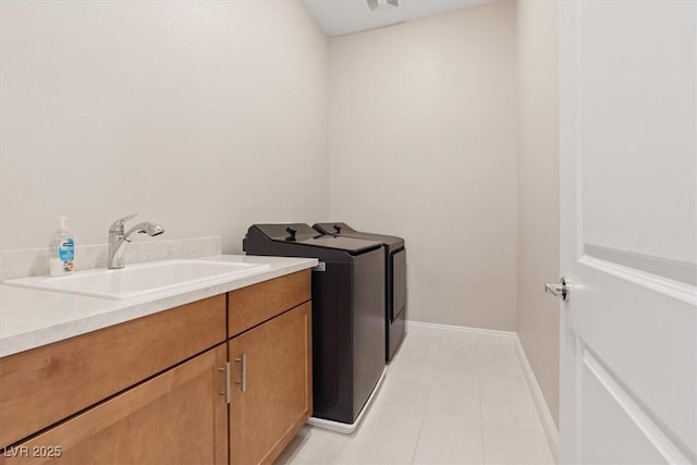 washroom with sink, light tile patterned floors, cabinets, and washer and dryer