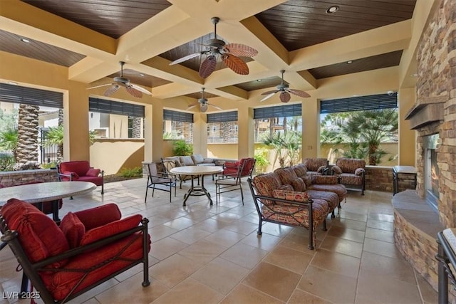 sunroom / solarium featuring beamed ceiling, coffered ceiling, and an outdoor stone fireplace