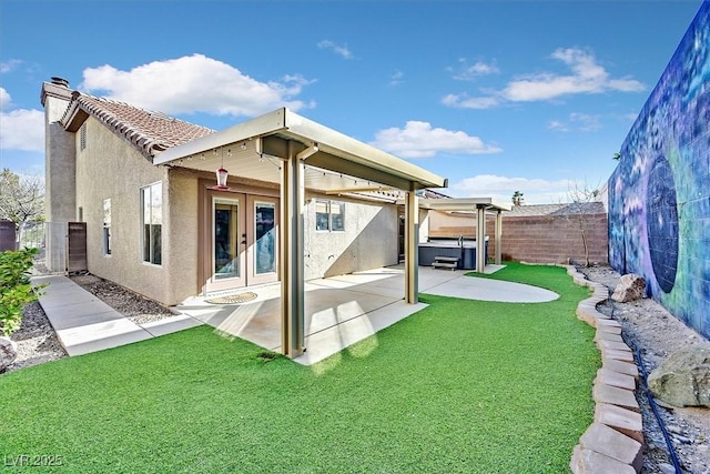 back of house with a lawn, a hot tub, a patio, and french doors